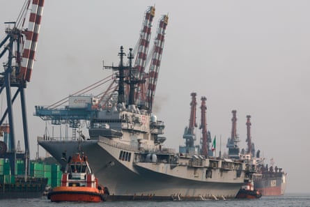 Small boat near aircraft carrier at a dock