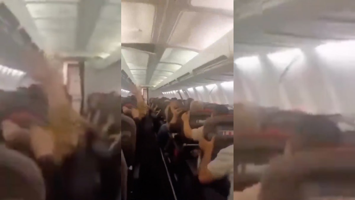 Passengers holding overhead compartments inside damaged aircraft.
