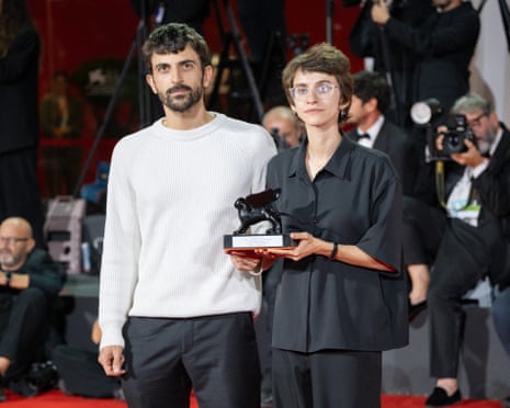 The directors hold a trophy in front of press photographers