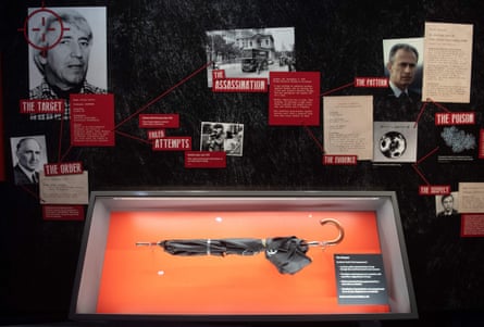 An umbrella in a museum display case under diagrammed photos and notes