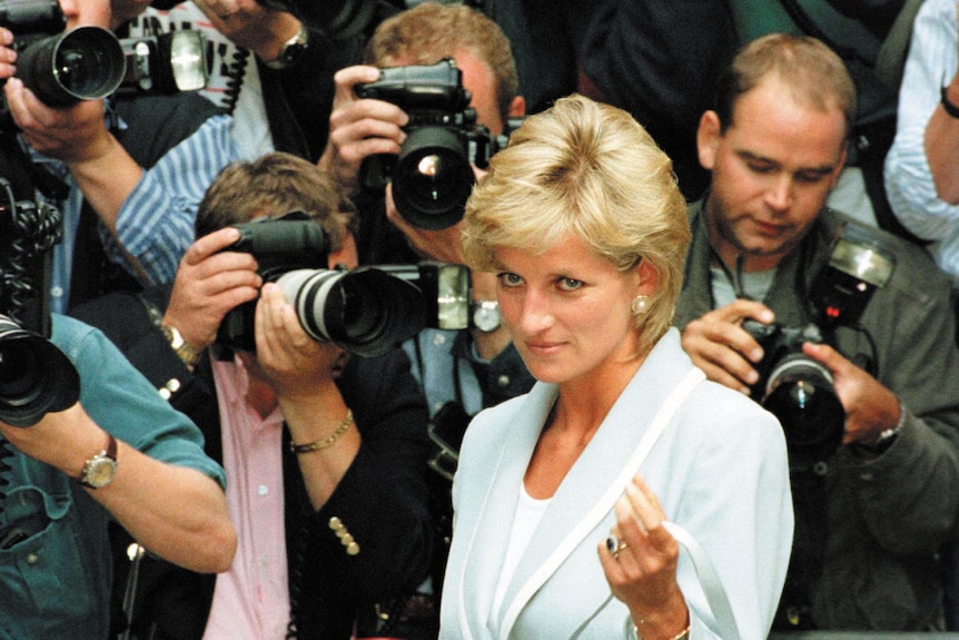 Princess Diana raises an eyebrow as she is surrounded by paparazzi with cameras.