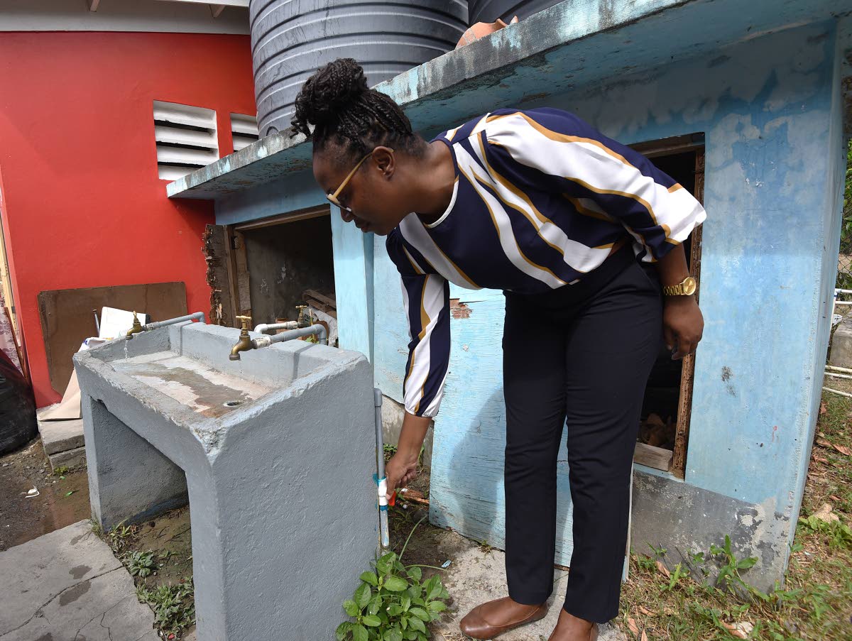 Cris Ann Francis, the acting principal of Springfield Primary School in St Thomas, turns on a lock off valve that was installed to prevent students from wasting water at the school.