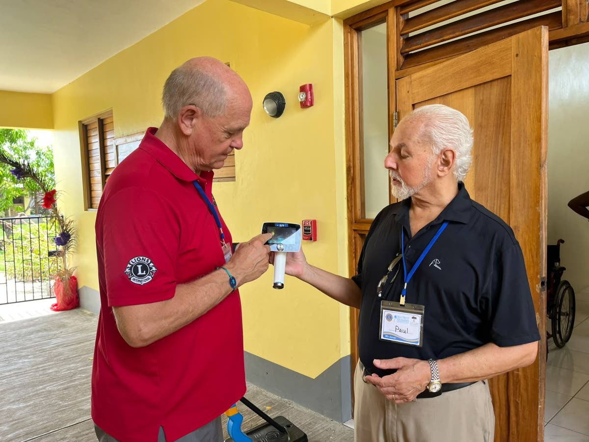 Gary Anderson (left), of the Lions of Michigan Foundation, and Paul Issa, chairman of the Issa Trust Foundation, with a retina camera at the Savanna-la-Mar Inclusive Academy.