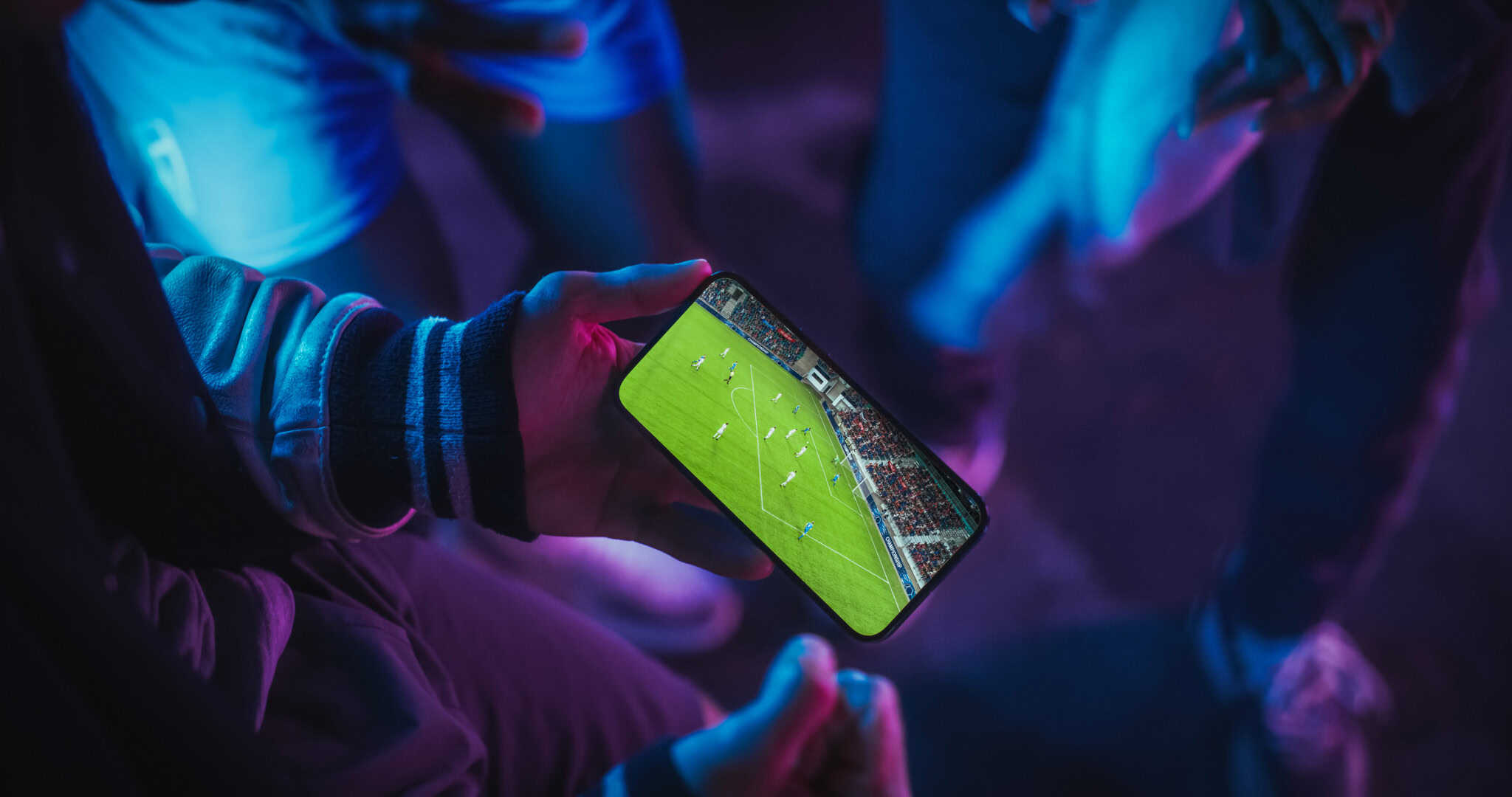 Pessoa segurando smartphone que mostra uma partida de futebol