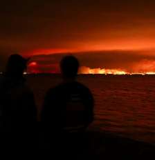Turistas observam incêndio florestal atingir uma área de mata próxima à baía de Arcachon, no oeste da França, em meio ao agravamento da seca após uma onda de calor e à escassez de água em grande parte do país, em 24 de julho de 2026. Foto: REUTERS - Stephane Mahe / RFI