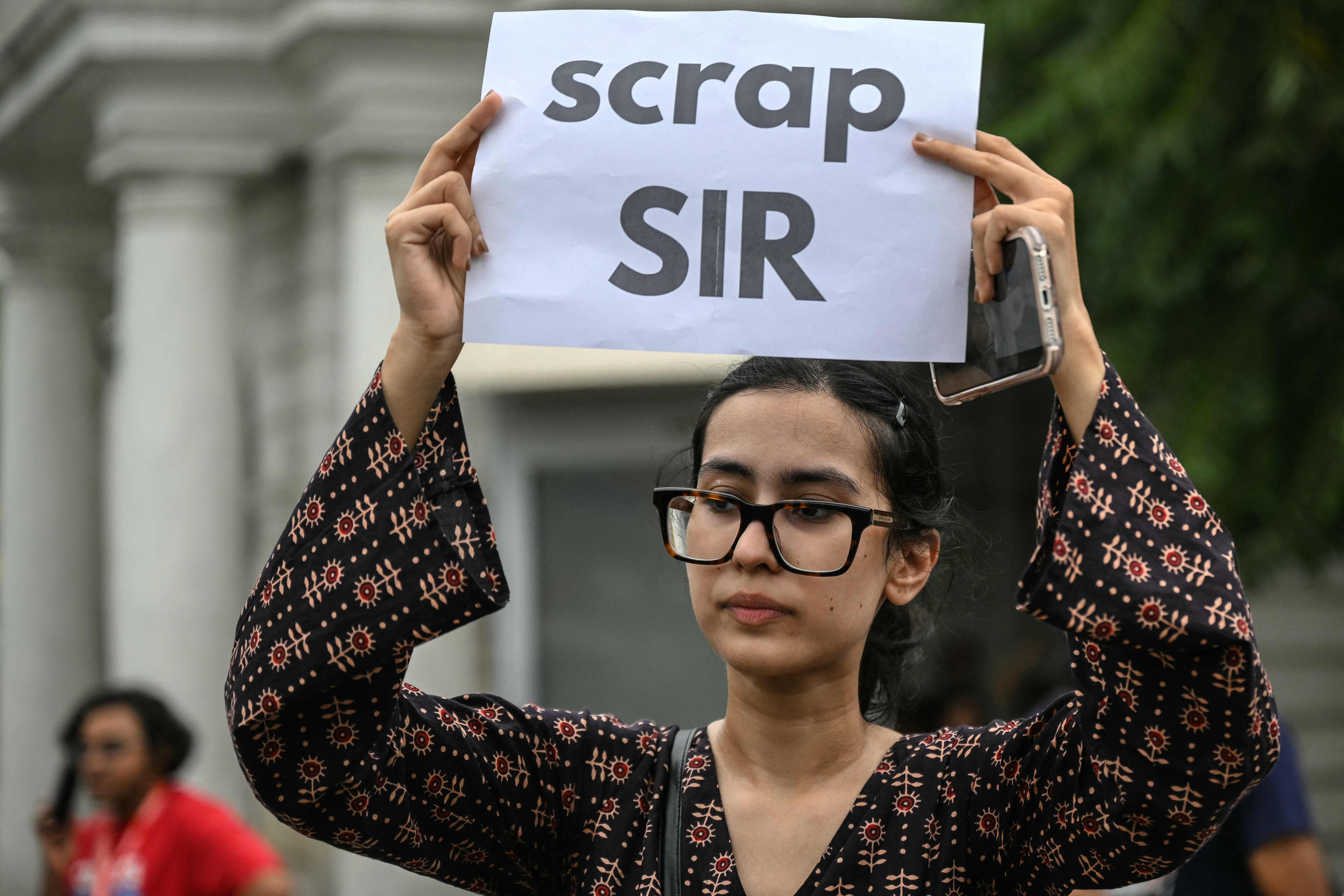 A demonstrator holds a placard during a protest demanding the resignation of India's Chief Election Commissioner Gyanesh Kumar over alleged voter roll irregularities linked to the "special intensive revision" (SIR), near Jantar Mantar in New Delhi on October 11, 2026. (AFP)