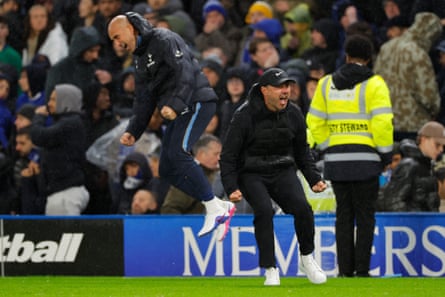 Roberto De Zerbi and a coach celebrate with clenched fists on a rainy touchline