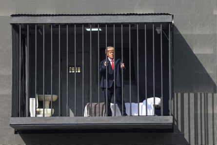 An Iranian actor in a Trump mask stands behind bars in a mock prison cell billboard